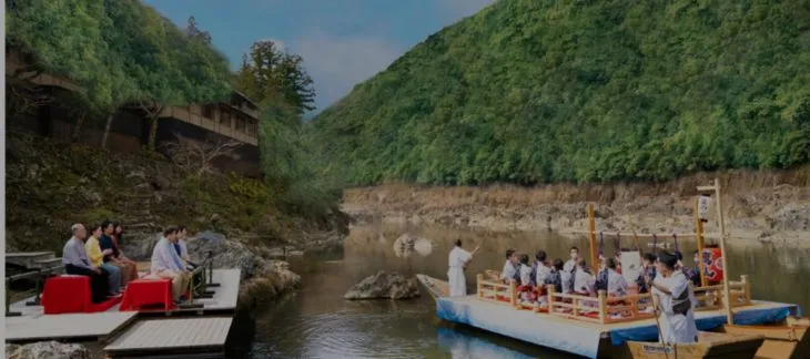 Traditional wooden boat arriving at the riverside Hoshinoya Kyoto resort
