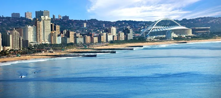 Golden Mile beachfront in Durban with palm-lined promenade and ocean surfers