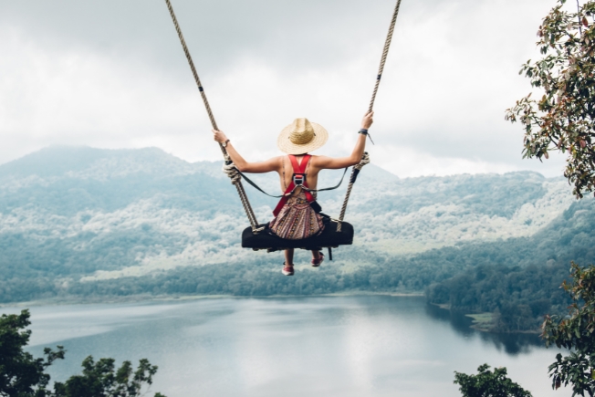 Arooha guest tourist enjoying freedom on swing in Bali, Indonesia