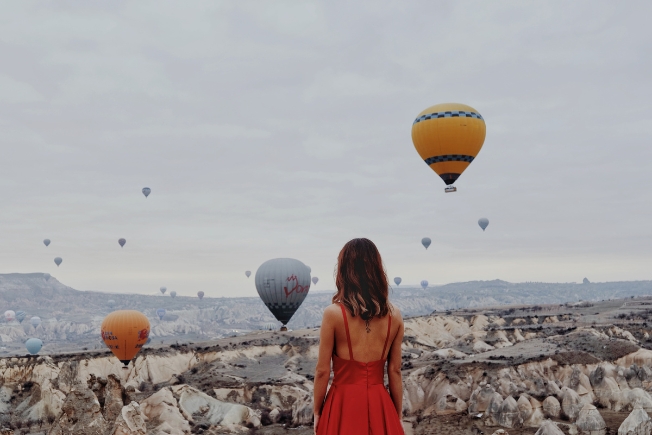 Arooha guest woman in red dress looking at floating hot air balloons in Turkey