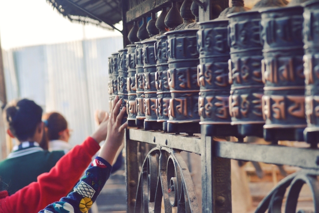 Arooha guest at pilgrims touching prayer wheels in temple in Nepal