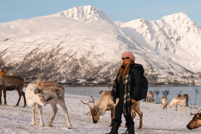 Arooha traveler enjoying a scenic winter day with reindeer in Tromsø during Norway tour packages from Dubai
